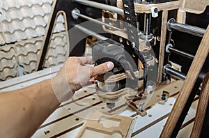 Man`s hand at the computer numerical control machine for wooden tools. CNC equipment for maintenance control and details