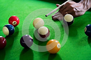 Man`s hand and Cue arm playing snooker game or preparing aiming to shoot pool balls on a green billiard table