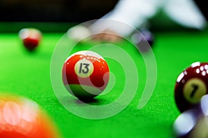 Man`s hand and Cue arm playing snooker game or preparing aiming to shoot pool balls on a green billiard table