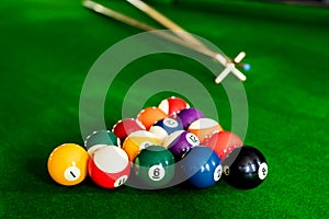 Man`s hand and Cue arm playing snooker game or preparing aiming to shoot pool balls on a green billiard table