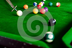 Man`s hand and Cue arm playing snooker game or preparing aiming to shoot pool balls on a green billiard table