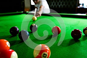 Man`s hand and Cue arm playing snooker game or preparing aiming to shoot pool balls on a green billiard table