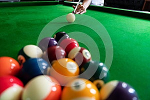 Man`s hand and Cue arm playing snooker game or preparing aiming to shoot pool balls on a green billiard table