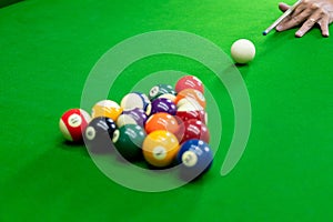 Man`s hand and Cue arm playing snooker game or preparing aiming to shoot pool balls on a green billiard table