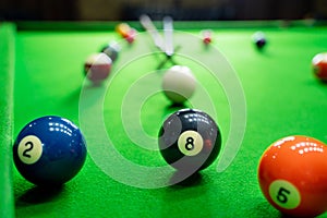 Man`s hand and Cue arm playing snooker game or preparing aiming to shoot pool balls on a green billiard table