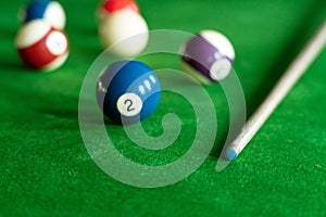 Man`s hand and Cue arm playing snooker game or preparing aiming to shoot pool balls on a green billiard table