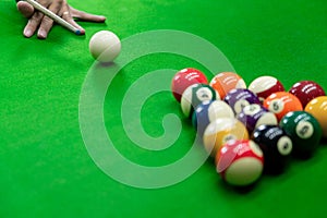 Man`s hand and Cue arm playing snooker game or preparing aiming to shoot pool balls on a green billiard table