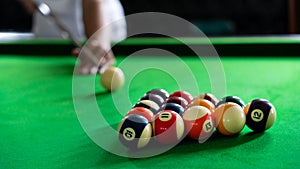 Man`s hand and Cue arm playing snooker game or preparing aiming to shoot pool balls on a green billiard table