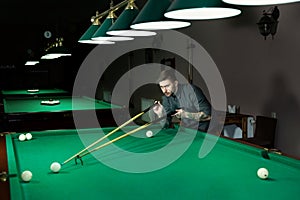 Man`s hand and Cue arm playing snooker game or preparing aiming to shoot pool balls on a green billiard table.