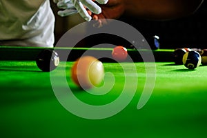 Man`s hand and Cue arm playing snooker game or preparing aiming to shoot pool balls on a green billiard table. Colorful snooker