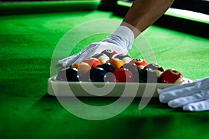 Man`s hand and Cue arm playing snooker game or preparing aiming to shoot pool balls on a green billiard table. Colorful snooker