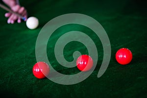 Man`s hand and Cue arm playing snooker game or preparing aiming to shoot pool balls on a green billiard table. Colorful snooker