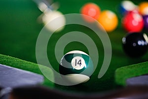 Man\'s hand and Cue arm playing snooker game or preparing aiming to shoot pool balls on a green billiard table. Colorful snooker