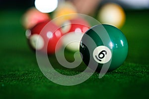 Man`s hand and Cue arm playing snooker game or preparing aiming to shoot pool balls on a green billiard table. Colorful snooker