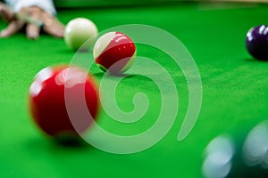 Man`s hand and Cue arm playing snooker game or preparing aiming to shoot pool balls on a green billiard table