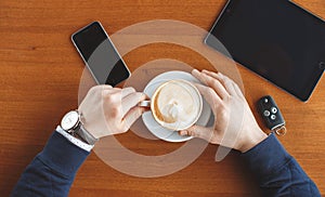 A man's hand,a Cup of coffee,tablet and car keys