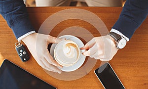 A man's hand,a Cup of coffee,tablet and car keys