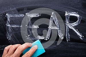 Man`s Hand Erasing Fear Word With Blue Sponge