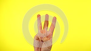 Man's hand with fingers counting from one to five, isolated on a yellow studio background