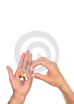 A man's hand is full of a large pile of different pills.