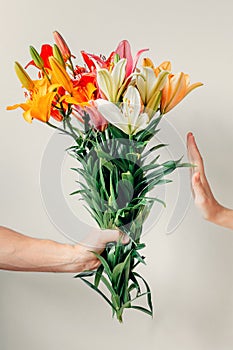 Man`s hand gives bouquet of lilies flowers to girl and receives refusal