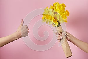 Man`s hand gives bouquet of yellow narcissus flowers to girl and receives refusal, woman shows OK sign