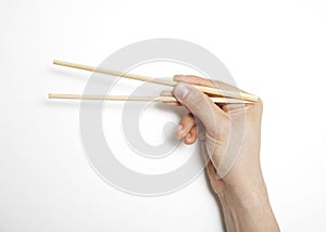 Man's hand gripping chopsticks over white background