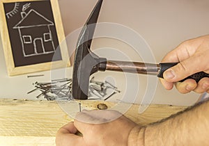 Man's hand hammering nail in wood