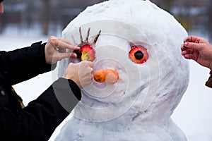 Man`s hand hold a big carrot, the nose of a real big snowman in wintere