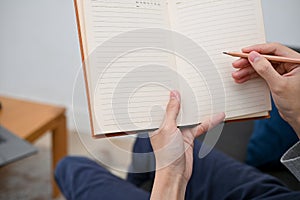 A man`s hand holding a blank empty diary book, writing diary or taking notes on a book