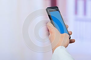 Man's hand holding cell phone with empty blue