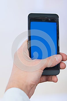 Man's hand holding cell phone with empty blue