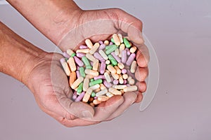 Man`s hand holding colorful pills isolated on white background.