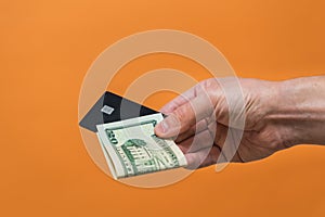 Man's hand holding credit card and dollars banknote with copy space. Money or Business concept