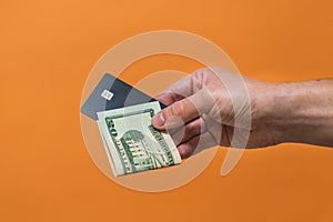 Man's hand holding credit card and dollars banknote with copy space. Money or Business concept