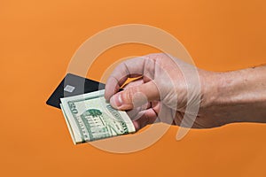 Man's hand holding credit card and dollars banknote with copy space. Money or Business concept