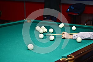 A man`s hand holding a cue at the time of aiming a billiard party