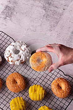 Man's hand holding a delicious donut in the bakery full of glazed donuts of San Isidro