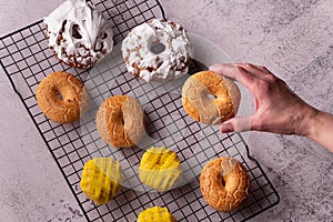 Man's hand holding a delicious donut in the bakery full of glazed donuts of San Isidro