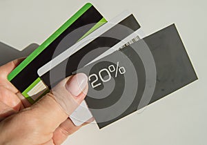 A man& x27;s hand holding a discount card with a 20 percent discount and a copy of the place and several plastic bank cards