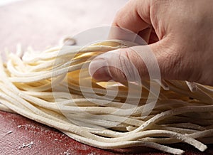 A man`s hand holding fresh udon noodles