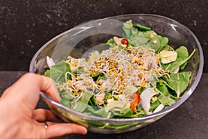 ManÂ´s hand holding a glass bowl of Soy sprouts salad