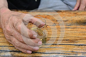 Man`s hand holding glass of good, old plum brandy