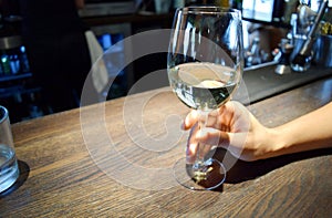 Man's hand holding glass of white wine