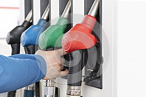 Man`s hand holding handle of gas pump on gasoline station