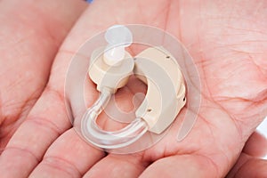 Man's Hand Holding Hearing Aid