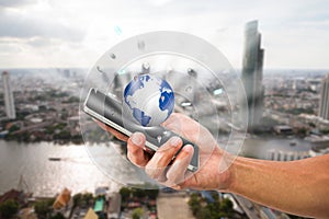 Man`s hand holding mobile phone with globe on blurred city background