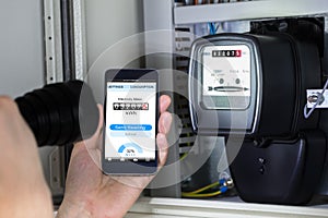 Man`s Hand Holding Mobile Phone Showing Electric Meter Reading