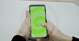 Man`s hand holding a mobile telephone with a vertical green screen in tram chroma key smartphone technology cell phone