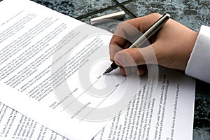 Man's hand holding a pen writing a signature